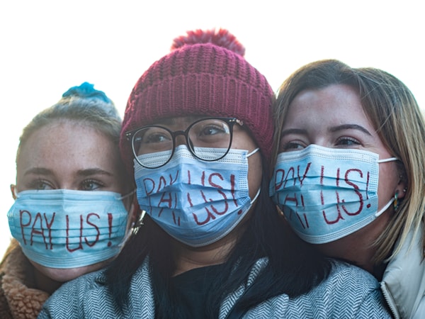 Student nurse holding a sign that says education not exploitation